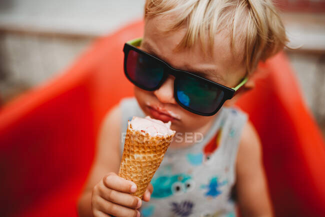 White blonde toddler eating ice cream cone with sunglasses — Stock Photo