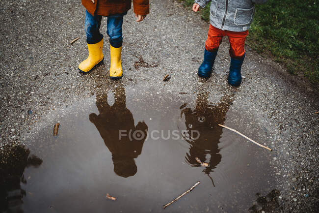 Blick von oben auf kleine Kinder in Regenstiefeln auf einer Pfütze — Stockfoto