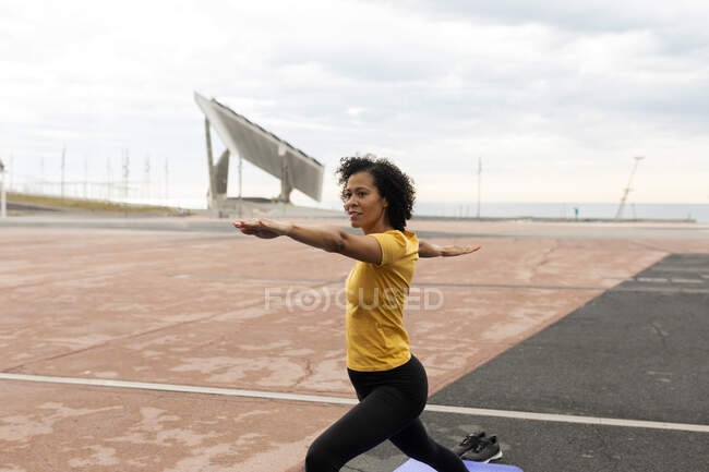 Mujer latina practicando yoga guerrero posan al aire libre - foto de stock