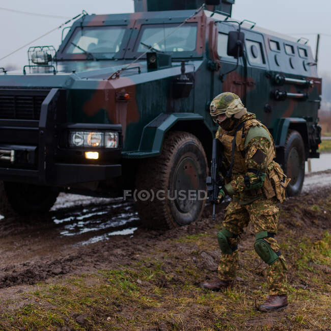 Современный украинский солдат движется под прикрытием бронеавтомобиля — стоковое фото
