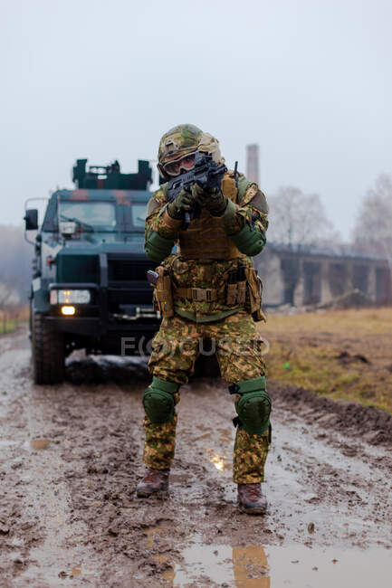 Ukraine modern soldier patrolling with a machine gun in his hands and an armored car - foto de stock