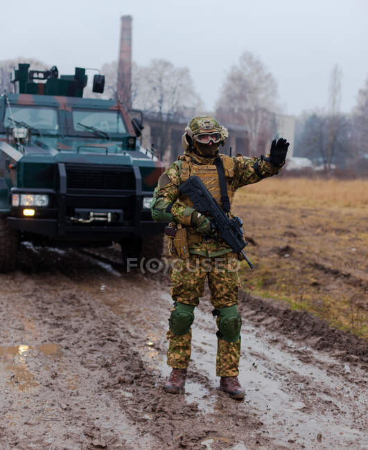Ukraine modern soldier stops the car with a machine gun in his hands and an armored car - foto de stock