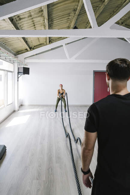 Junge Frau trainiert mit ihrem Trainer im Fitnessstudio — Stockfoto
