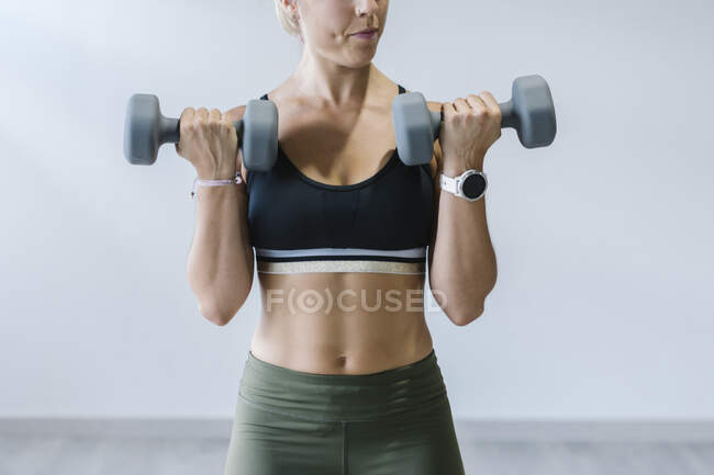 Femme soulevant haltères dans la salle de gym — Photo de stock