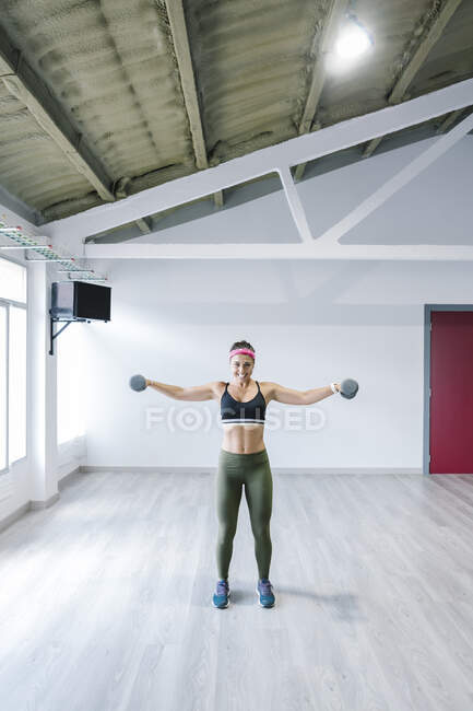 Blonde Frau trainiert mit Kurzhanteln im Fitnessstudio — Stockfoto