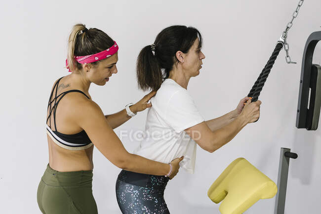 Зрелая женщина со своим тренером тренируется в спортзале — стоковое фото