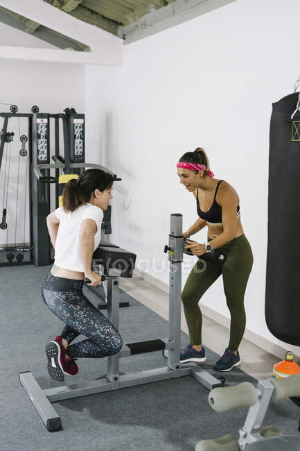 Entraîneur féminin motivant femme mûre pendant l'entraînement en salle de gym — Photo de stock