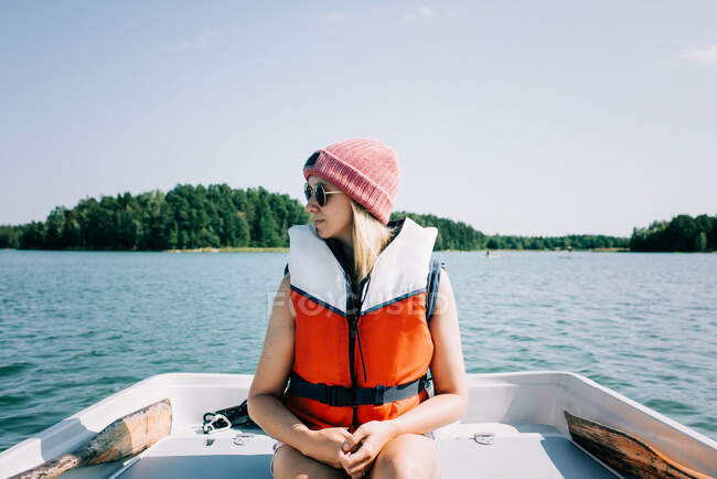 Femme assise paisiblement sur un bateau à rames en été sur un lac — Photo de stock