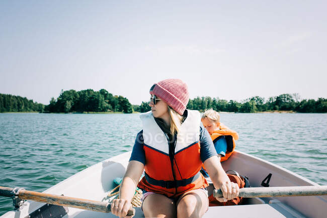 Femme ramant un bateau avec ses enfants en Suède en été — Photo de stock
