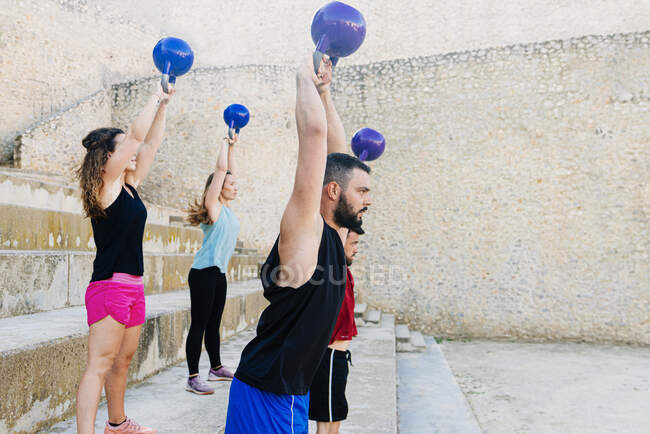 Atletas levantando um kettelbell crossfit pesos em um ambiente urbano. — Fotografia de Stock