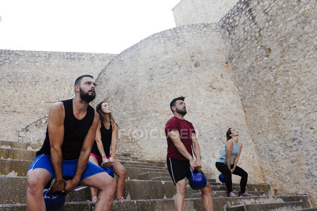 Спортсмены, поднимающие гири-кроссфит в городской среде. — стоковое фото