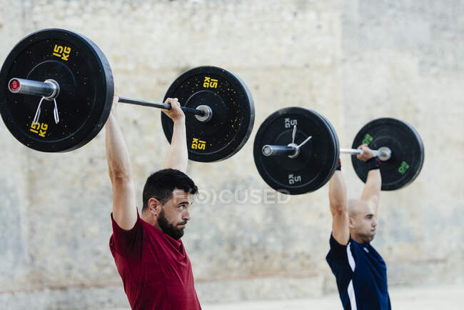 Zwei Gewichtheber heben Gewichte in einer städtischen Umgebung. — Stockfoto
