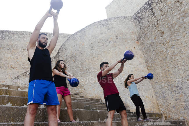 Athletes lifting a kettelbell crossfit weights in an urban enviroment. — Stock Photo