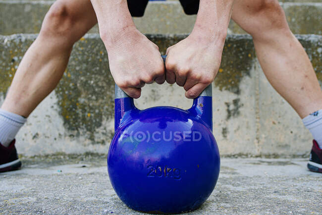 Man lifting a kettelbell crossfit weight in an urban enviroment. — Stock Photo