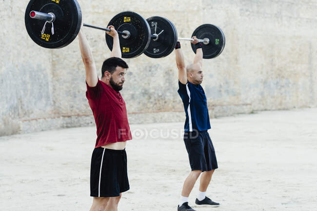 Zwei Gewichtheber heben Gewichte in einer städtischen Umgebung. — Stockfoto