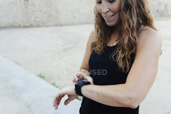Junge Frau stellt Uhr auf, bevor sie urbanes Crossfit übt. — Stockfoto