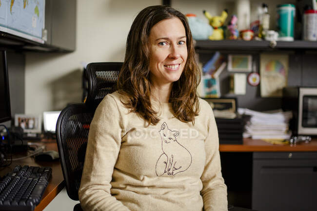 Професор жінки сидить за своїм офісним столом, усміхаючись прямим поглядом. — Stock Photo