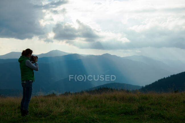 Ragazza fotografo nelle montagne carpatiche scatta un paesaggio — Foto stock