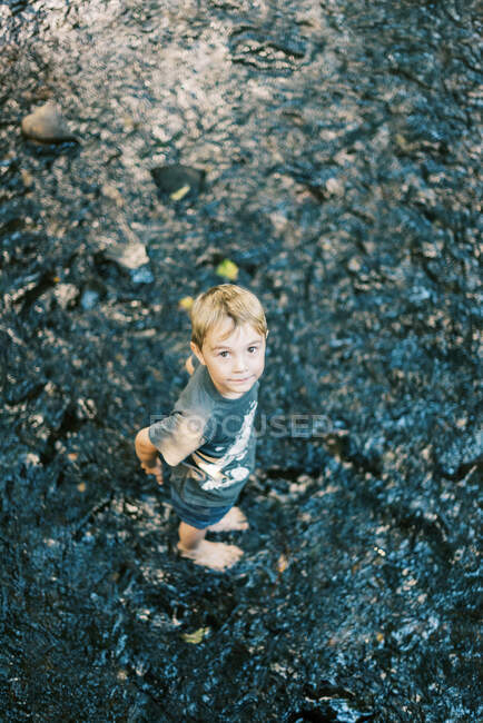 Ein fünfjähriger Junge bekommt nasse Füße in einem Fluss — Stockfoto