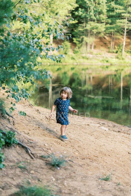 A two year old girl exploring a local pond in the woods — Stock Photo