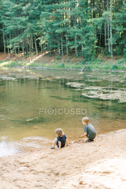 Two children exploring nature at a local pond in the woods — Stock Photo