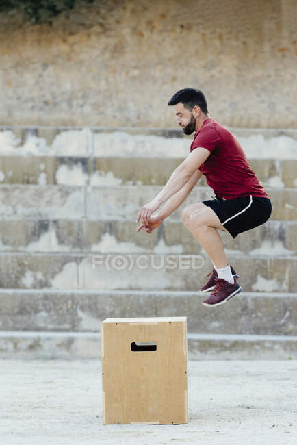 Uomo che pratica il crossfit saltando in una scatola piometrica. — Foto stock