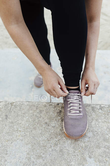 Close up of young woman's hands tying her shoes before sport. — Stock Photo