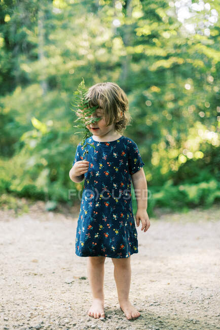 Zweijähriges Kleinkind spielt im Wald mit Farnblatt — Stockfoto