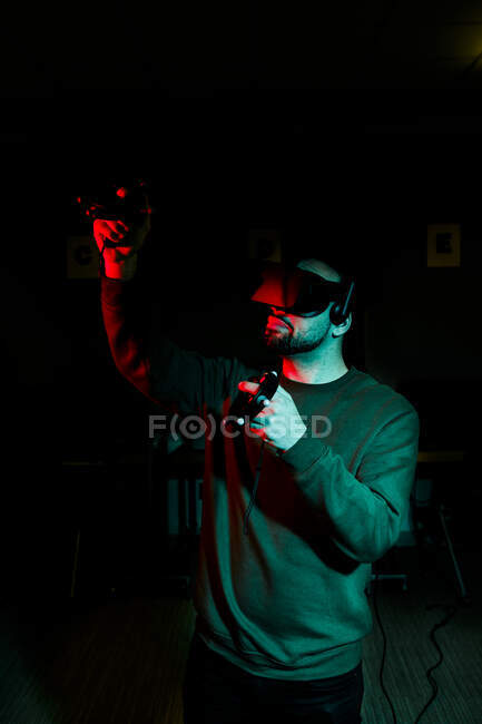 Чоловік стоїть у темній кімнаті в обладнанні віртуальної реальності та окулярах — стокове фото