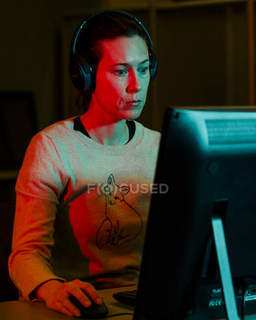 Ritratto di una donna con le cuffie incentrate su un computer desktop — Foto stock