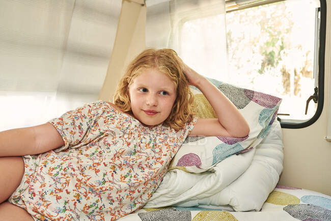 Uma rapariga deitada numa caravana. Ela está relaxada em suas férias. — Fotografia de Stock