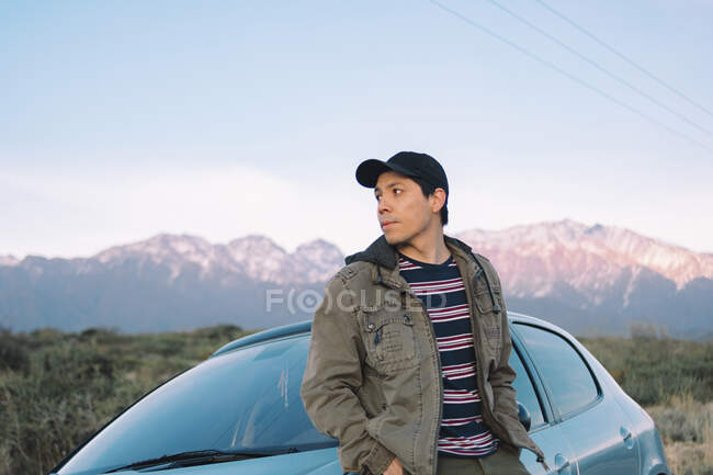 Liegender junger Mann sitzt im Auto und bewundert die bergige Landschaft. — Stockfoto