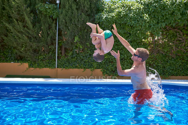 Vacances d'été. Père et fils jouent dans une piscine. — Photo de stock
