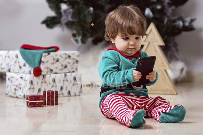Bambino di 12 mesi vestito da elfo con smartphone a casa — Foto stock