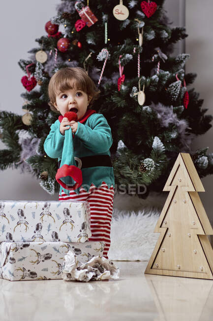 A little 12-month-old Christmas elf with a Christmas tree and gifts — Stock Photo