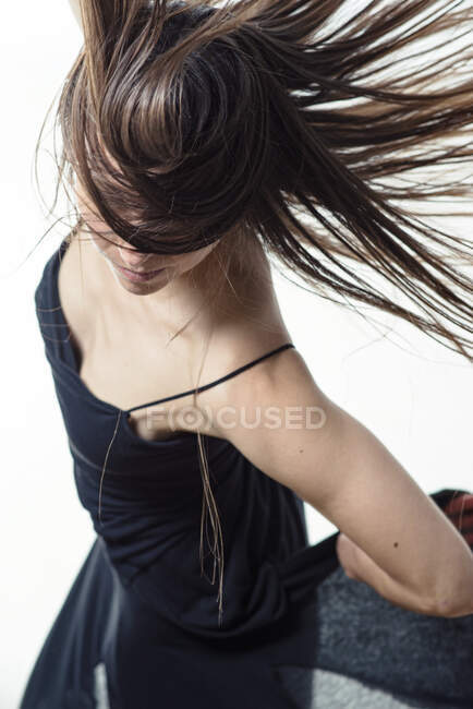Jeune femme dansant avec des cheveux volants dans une robe noire volante — Photo de stock