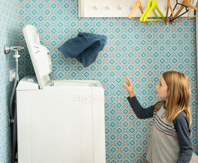 Chica lanzando la lavandería en la lavadora en Helsinki, Finlandia - foto de stock