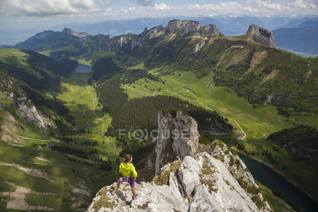 Escalador de rocas en la cumbre sobre el valle, Alpstein, Appenzell, Suiza - foto de stock