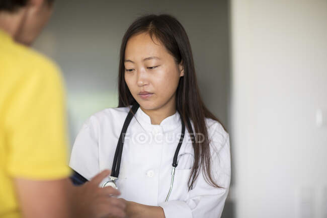 Молода жінка-лікар Азії з пацієнткоюЗвіт на практиці — стокове фото