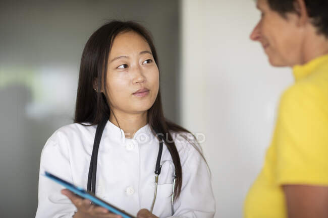 Mujer joven asiática médico mujer y paciente con informe en una práctica - foto de stock