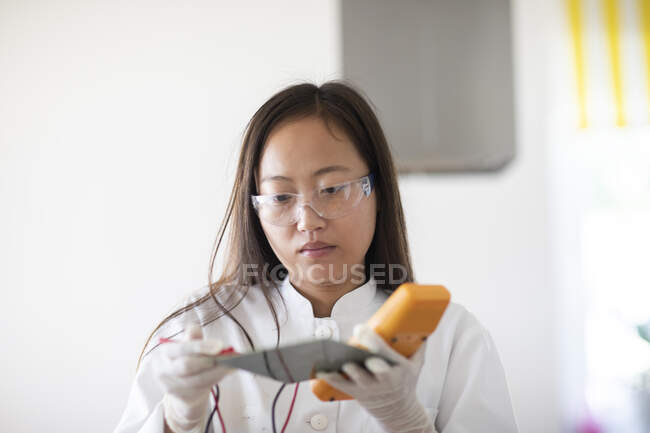Scienziata femmina con campione e attrezzo in laboratorio — Foto stock