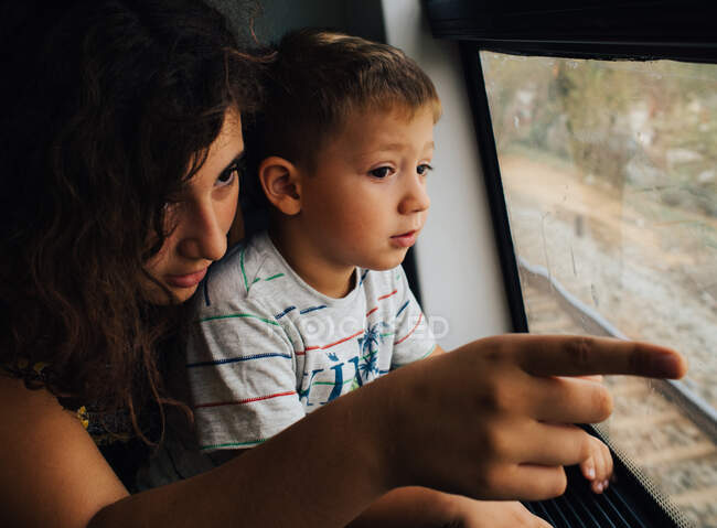 Девочка со своим младшим братом смотрит в окно поезда — стоковое фото