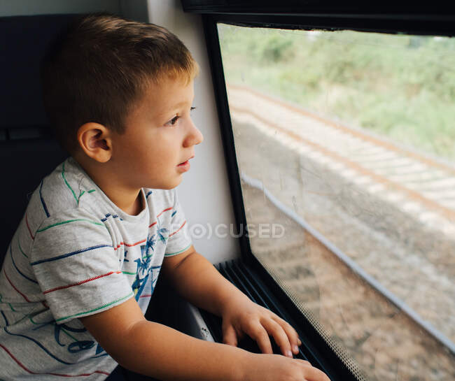 Menino olhando através da janela do trem animado sobre a viagem — Fotografia de Stock
