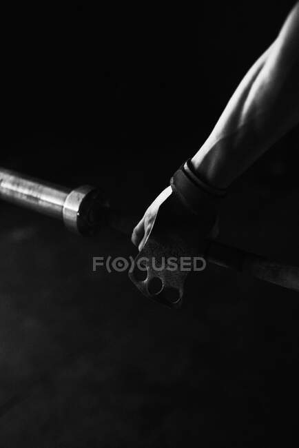Hand holding a horizontal bar with a glove at indoors gym — Stock Photo