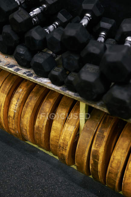 Dumbbells and heavy discs bunched together at indoors gym — Stock Photo