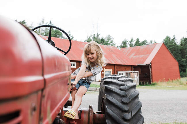 Девушка сидела на тракторе улыбаясь во время фермы в Швеции — стоковое фото