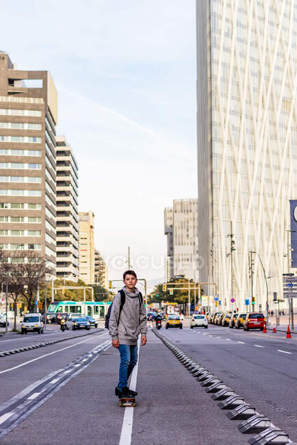 Вид спереду молодого підлітка з рюкзаком скейтбординг на міській вулиці — стокове фото