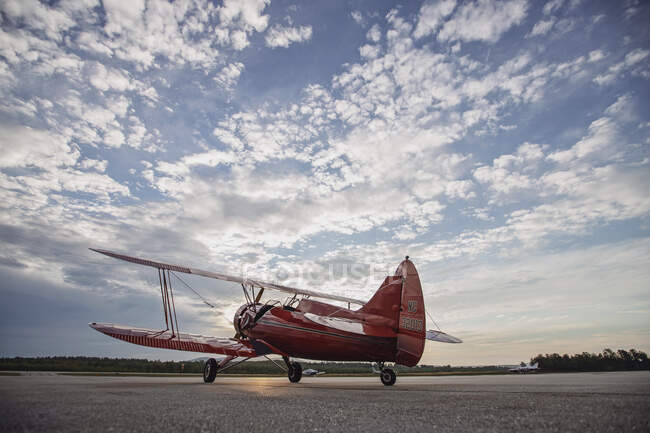 Винтажный красный самолет Waco сидит на взлетно-посадочной полосе на восходе солнца в штате Мэн — стоковое фото