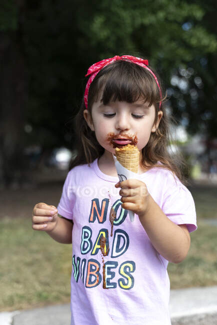 Little girl eating chocolate ice cream witn no bad vibes t-shirt — Stock Photo