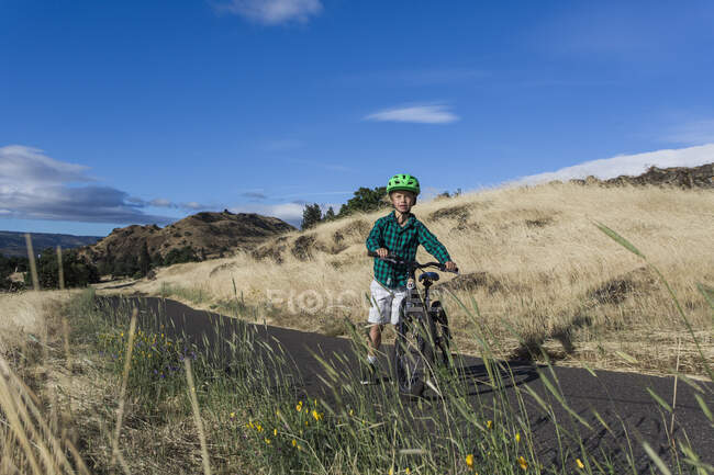 A young boy rides his bike with his mom in the Columbia Gorge. — Stock Photo